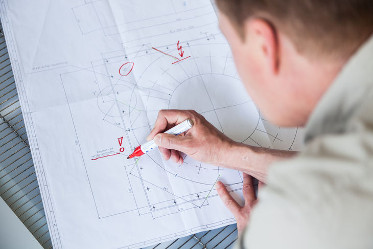 Ingenieur markiert technische Zeichnung für Industriefilter mit rotem Stift Ingenieur markiert technische Zeichnung für Industriefilter mit rotem Stift