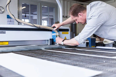 Mitarbeiter bedient industrielle Schneidemaschine zur Herstellung von Filtertüchern